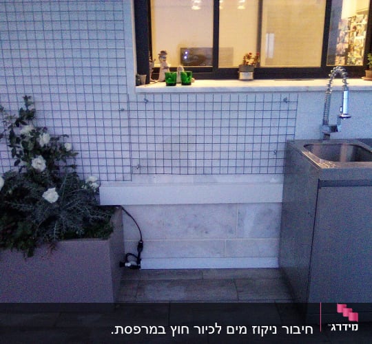 כיור נירוסטה עם ברז גבוה ליד חלון